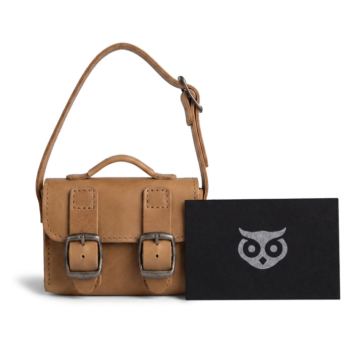 The tan Tiny Messenger Bag by Hide & Drink, presented with its tags. This artisanal Mini Messenger Bag Charm in Full Grain Leather is a useful keychain or handbag accessory, carefully made in La Antigua Guatemala.