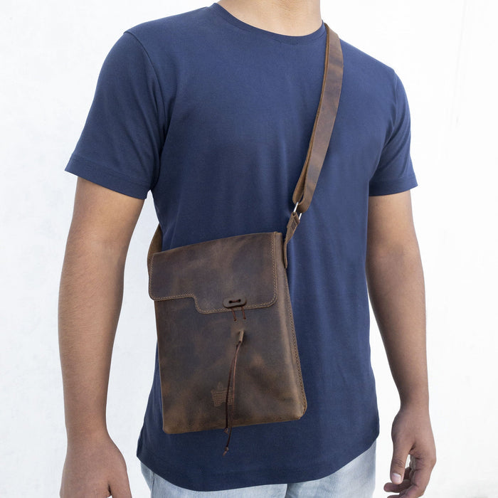 A person wearing the La Antigua Treasure Crossbody Bag, featuring a rustic style and an adjustable shoulder strap. This full grain leather vintage satchel is ideal for daily use and travel. Handmade in La Antigua Guatemala with artisan craftsmanship.