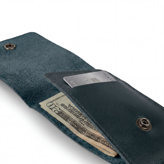 Back view of the blue Vertical Wallet by Hide & Drink featuring the embossed logo. This Vertical Front Pocket Wallet with Card Slot merges fashion with function, enabling compact storage for bills and cards, crafted from full grain leather utilizing small batch production techniques, hand cut, and hand sewn with fire branding. Handmade in La Antigua Guatemala & Oaxaca Mexico.