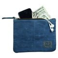 A blue Waxed Zippered Pouch by Hide & Drink, filled with a phone, cash, and earbuds, exemplifying its multi-functional use. This Canvas Zippered Pouch is a lightweight case crafted in Oaxaca Mexico, combining waxed canvas and full grain leather.