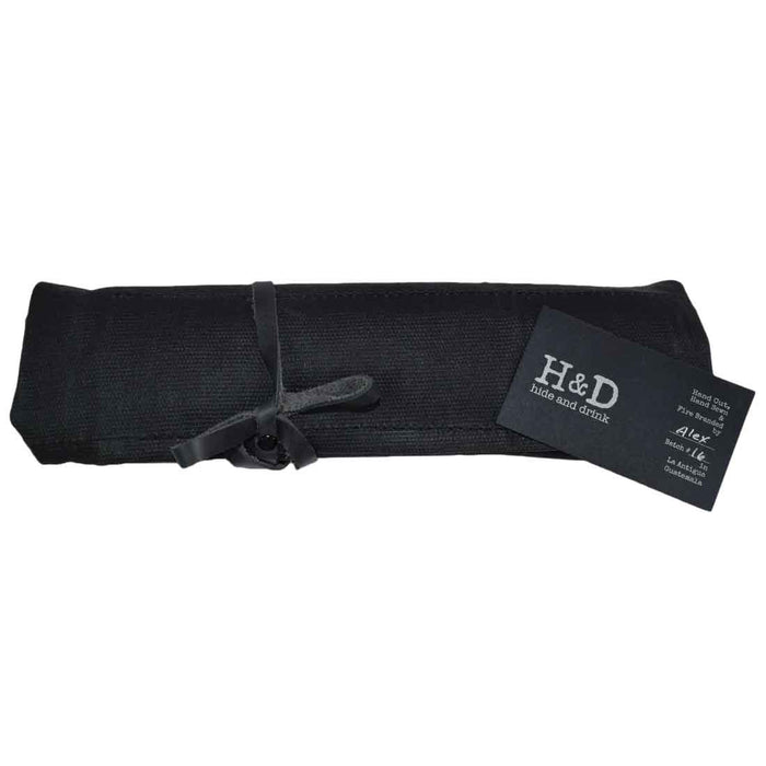 Hide & Drink's Wrench Roll (11 Pockets) rolled and secured with a leather strap, showcasing its convenient portability. This Wrench Tool Roll is perfect for craftsmen who need reliable hanging storage for tools. Made from high-quality waxed canvas, it serves as a rustic organizer featuring small batch production, hand cut and hand sewn artistry, and fire branding, crafted in La Antigua Guatemala & Oaxaca Mexico.