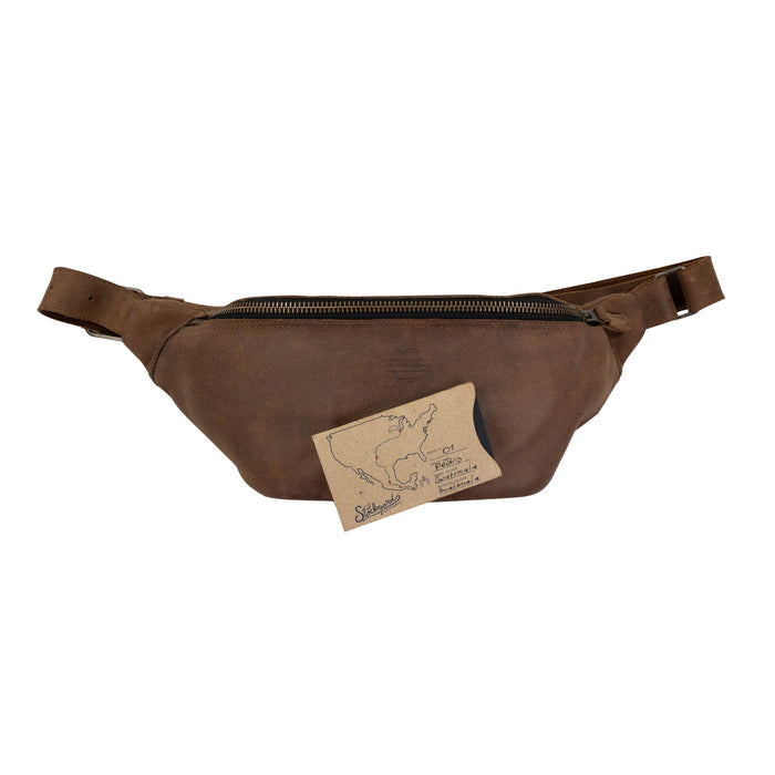 Zippered Fanny Pack by Leather Nomad in a natural setting. This handmade bag is crafted from full grain leather and serves as a stylish waist bag for travel, offering storage for money and phone. Artisan quality is evident in its small batch production, hand cut, and hand sewn features from La Antigua Guatemala.